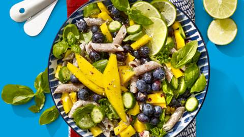 Frisse volkorenpastasalade met mango, blauwe bessen, limoen, groene kruiden en snackkomkommer