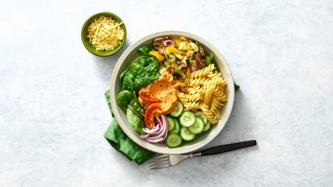 Vegan pastabowl met spinazie, geroosterde groenten en houmous-zongedroogde tomaten