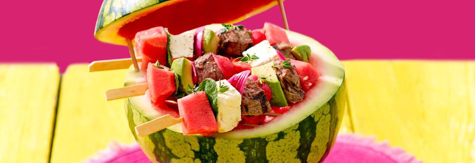 Zomerse prikkers met biefstuk, watermeloen, avocado en feta geserveerd op een watermeloen-BBQ