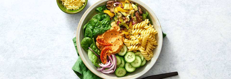 Vegan pastabowl met spinazie, geroosterde groenten en houmous-zongedroogde tomaten