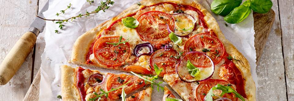 Huisgemaakte pizza met trostomaten, mozzarella en basilicum